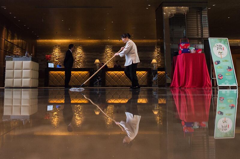 A worker cleans the floor of a hotel in Beijing.  Nicolas Asfouri / AFP Photo