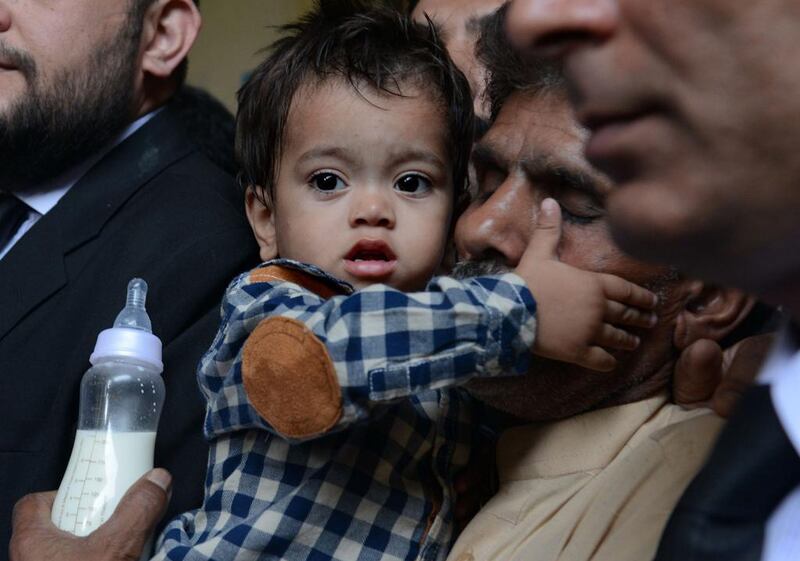 Nine month Pakistani toddler Mohammad Musa is held by his grandfather Muhammad Yasin, during a court hearing in Lahore on April 12. Arif Ali / AFP Photo

