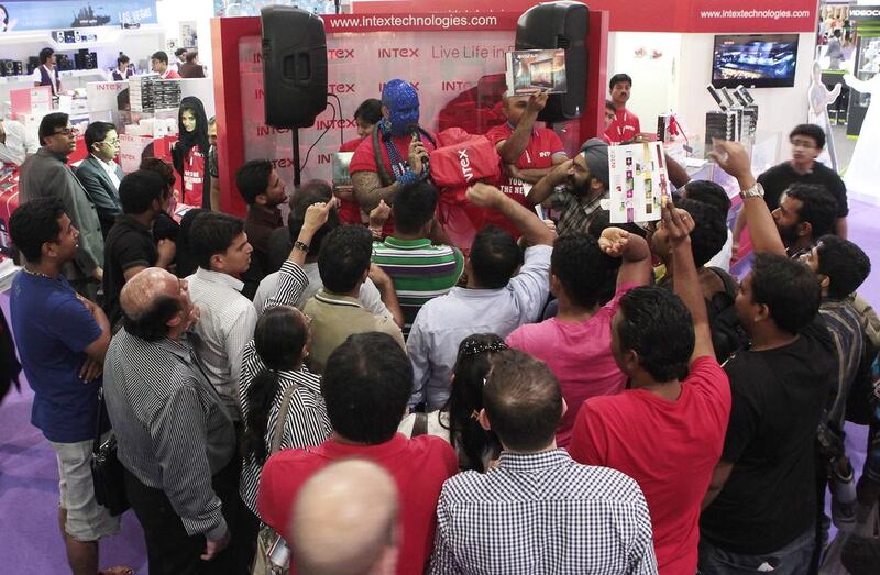 Loy Machedo, covered in sparkling blue glitter paint, leads the bidding of electronic devices at Intex Technologies as enthusiastic shoppers bid for items from Dh1 at Gitex Shoppers 2013. Jeffrey E Biteng / The National