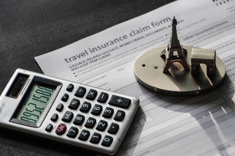 High Angle View Of Figurine And Calculator On Travel Insurance Form (Getty Images) *** Local Caption ***  wk30de-tr-tips08.jpg
