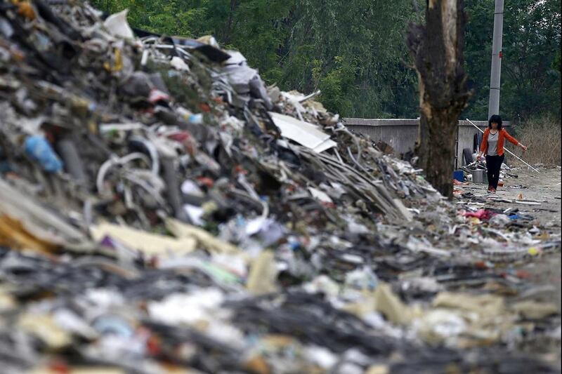 A woman walks near mounds of garbage, which were abandoned by recycling workers, at Dongxiaokou village. Kim Kyung-Hoon / Reuters