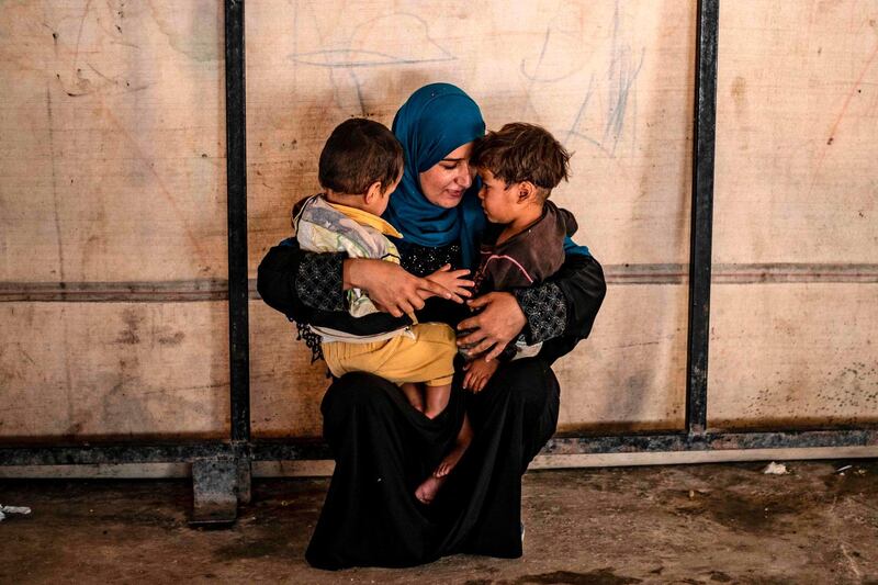 TOPSHOT - Sara al-Abdullah, a volunteer caring for 24 orphaned children reportedly linked with foreign fighters of the Islamic State (IS) group, holds two of them at a camp in the northern Syrian village of Ain Issa, on September 26, 2019. The Kurdish authorities in northeast Syria have repeatedly called for their foreign detainees to be repatriated, but this has largely been met with resistance, except in the rare case of dozens of orphans. / AFP / Delil SOULEIMAN
