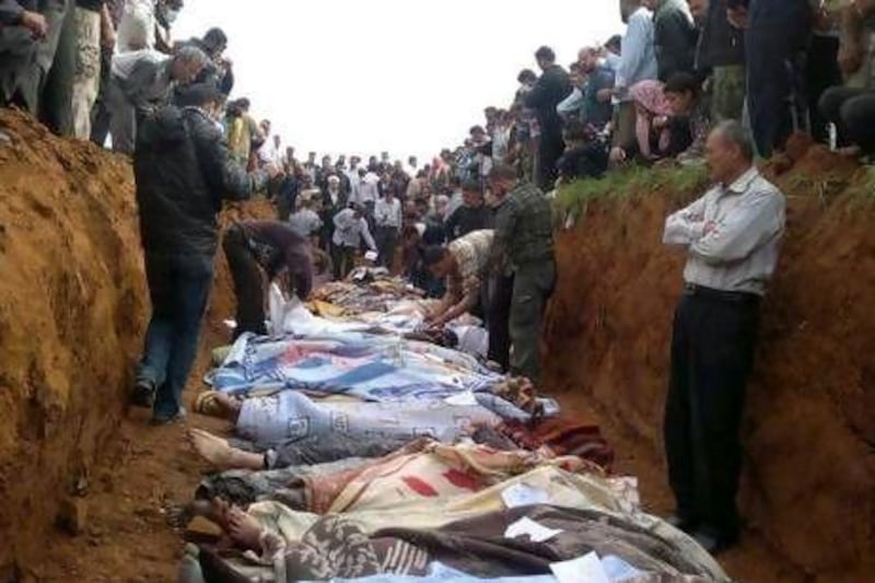 A picture released from the Local Coordination Committees in Syria purportedly shows people standing around a mass grave in the town of Taftnaz on Thursday.