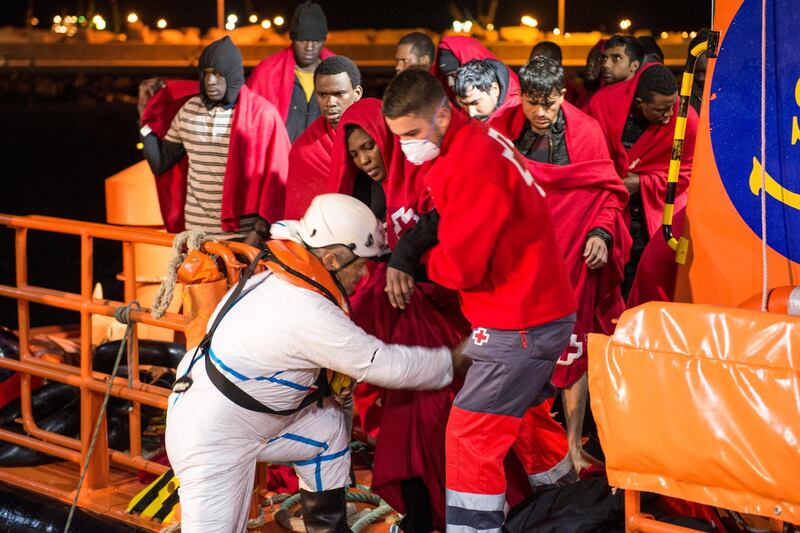 A Spanish coast guard and a member of the Spanish Red Cross help disembark migrants after dozens of them were rescued in a raft off the coast at the Mediterranean Sea, at the port of the Spanish North African enclave of Melilla, November 27, 2019. REUTERS/Jesus Blasco de Avellaneda