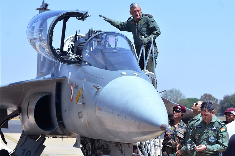 This image taken on February 21, 2019 shows Gen Rawat waving as he gets into the co-pilot seat of a Light Combat Aircraft during the Aero India air show in Bangalore.  AFP