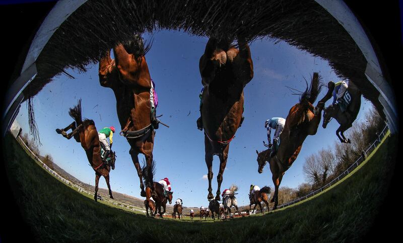 Runners and riders clear a fence during the Johnny Henderson Grand Annual Challenge Cup Handicap Chase on Day 2 of the Cheltenham Festival in England on Wednesday March 17. PA