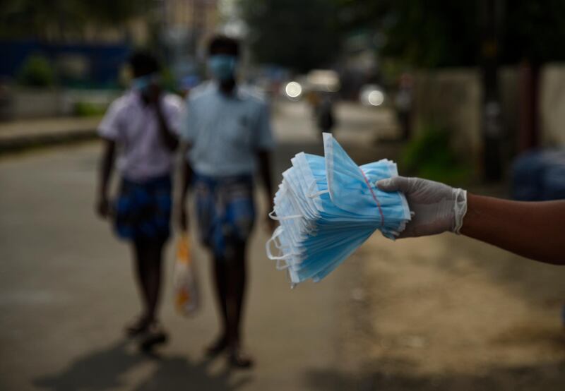 People wearing masks walk past a man selling face masks by a roadside in Kochi, Kerala, India, Saturday, May 2, 2020. The southern state has made wearing face masks mandatory in public places and work places as part of measures to curb the spread of the new coronavirus. (AP Photo/R S Iyer)