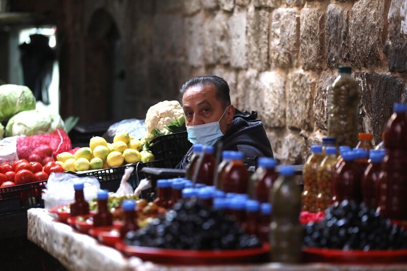 A Palestinian vendor wears a face mask while waiting for customers in Nablus, West Bank. EPA
