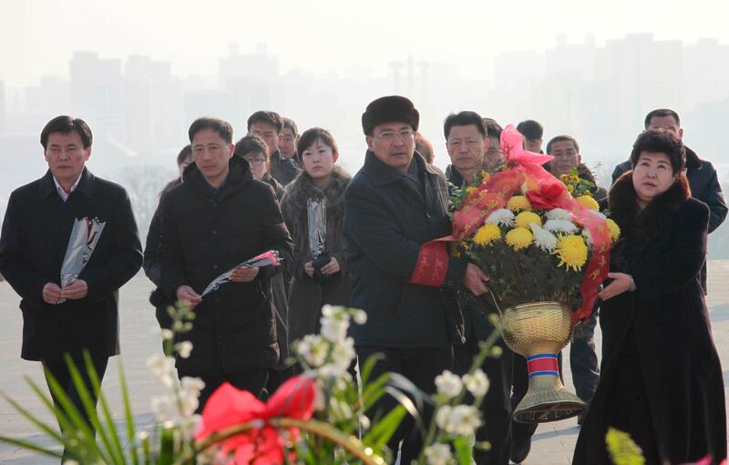 People carry flowers to lay below the statues of former North Korean leaders Kim Il Sung and Kim Jong Il on Mansu Hill in Pyongyang. (AP Photo/Jon Chol Jin)