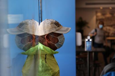A man wearing a mask is reflected in glass as he enters a pool where a "Green Badge" is required upon entry, as Israel reopens swathes of its economy, continuing to lift restrictions of a national lockdown to fight the coronavirus disease (COVID-19), at Gordon Gym and Pool in Tel Aviv, Israel February 21, 2021. REUTERS/Ronen Zvulun