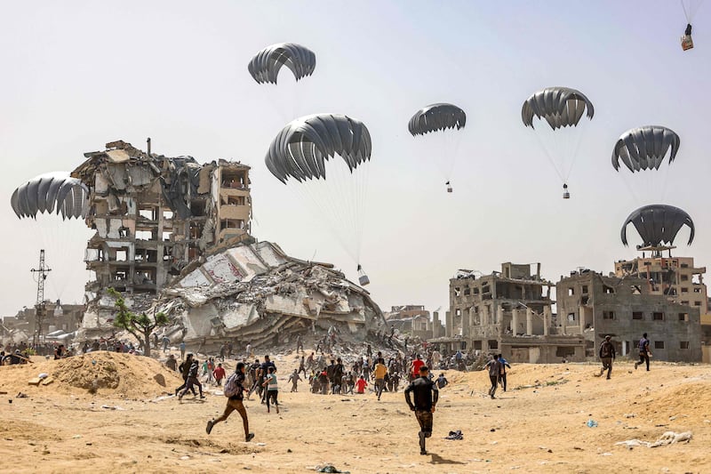 Palestinians rush to intercept humanitarian aid packages as they land in the northern Gaza Strip, dropped by a UAE plane in a joint effort with Egypt. All photos: AFP