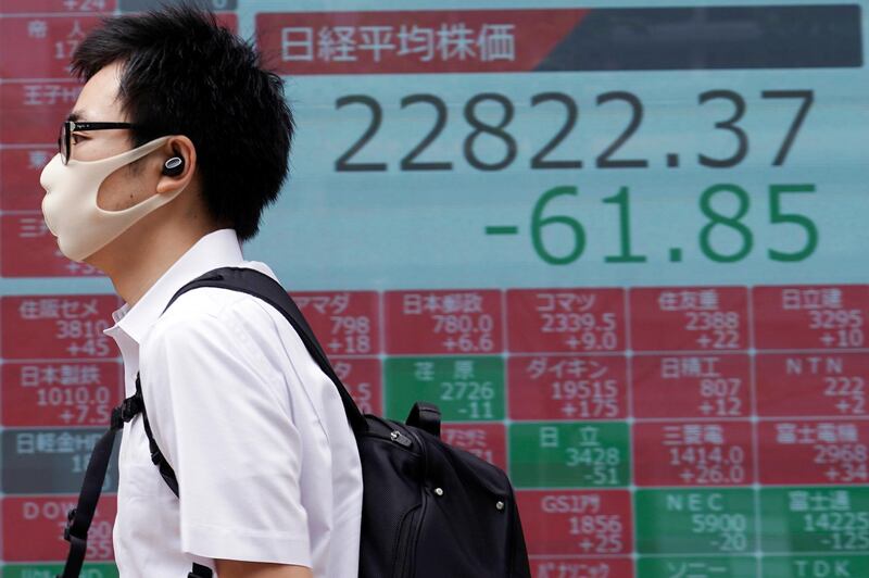 A man wearing a face mask walks past an electronic stock board showing Japan's Nikkei 225 index at a securities firm in Tokyo Wednesday, July 22, 2020. Shares were mixed in Asia on Wednesday, with Australiaâ€™s benchmark down more than 1% on reports of a sharp rise in coronavirus cases in the Melbourne area. (AP Photo/Eugene Hoshiko)