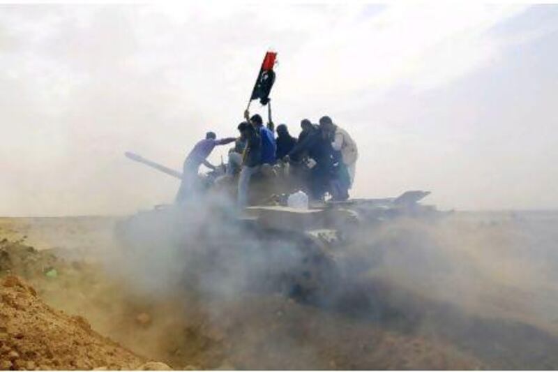 Rebels ride on top of a tank on the outskirts of Ajdabiya, on the road leading to Brega.