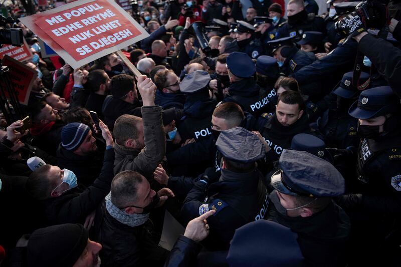 A proster holding a placard reading “Don't play with people and electricity, you can get burnt” scuffles with Kosovo police officers during a protest in Pristina against the increase of electricity prices in Kosovo.  AFP