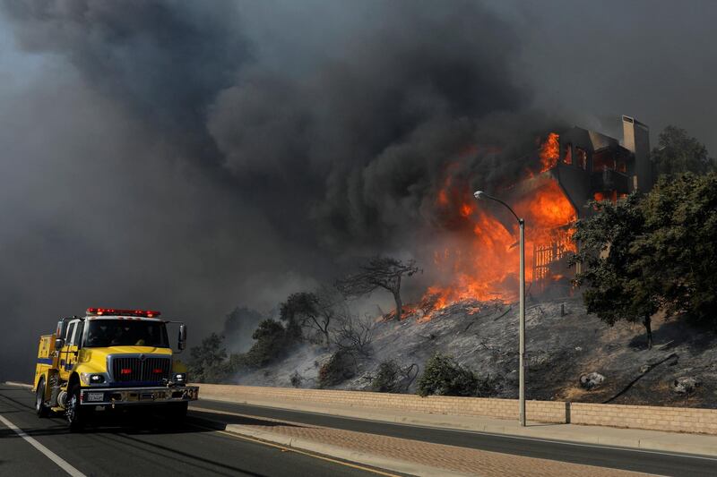 A fire crew passes a burning home during a wind-driven wildfire in Ventura, California. Mike Blake / Reuters