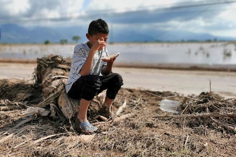 A child affected by tropical storms Eta and Iota eats on the side of a street in La Guadalupe, Honduras. EPA