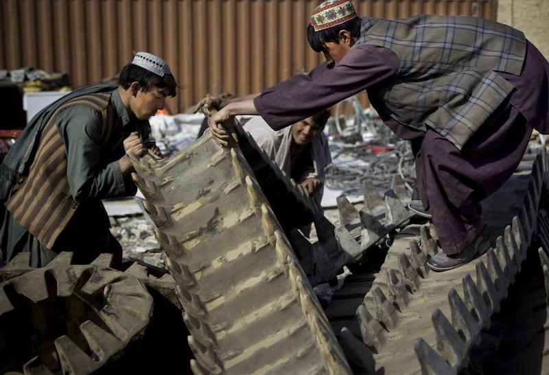 Afghan scrap dealers try to load giant rubber treads of a US tank received from the departing military as junk in Kandahar, southern Afghanistan.  Anja Niedringhaus / AP