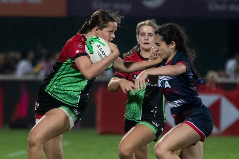 A Harlequins player fends off a tackle by a Dubai College opponent. 
