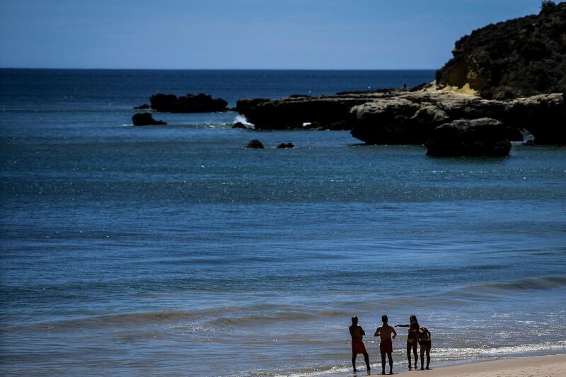People stand at Oura beach, Albufeira, in Algarve, south of Portugal.  British holidaymakers returned to Portugal on Monday as the country seeks to revive its battered tourism industry. AFP