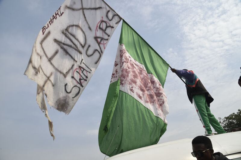 A protester raises the Nigerian flag alongside an EndSARS flag.  AFP