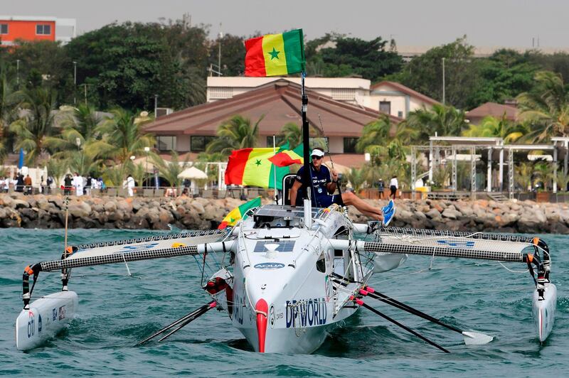 Patrick Bol, Dutch skipper of the Row4ocean rowing trimaran holds a Senegalese flag as his team leaves Dakar to cross the Atlantic on December 14, 2018. AFP