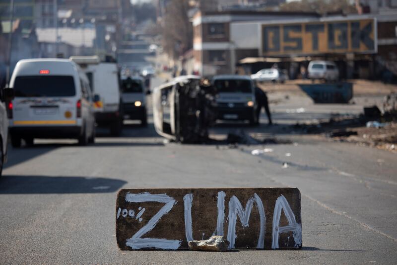A burnt car at a road block in downtown Johannesburg. Mr Zuma and the Gupta brothers, who fled the country after his departure from office, deny wrongdoing.