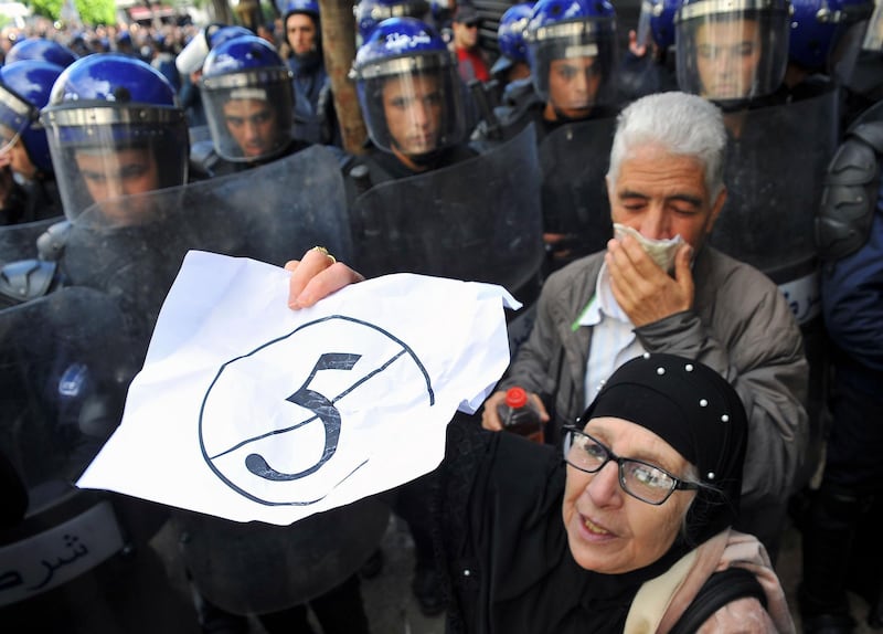 A demonstrator holds up a sign that reads, "no to a 5th term" as she stands next to riot police officers during a protest to denounce President Abdelaziz Bouteflika's bid for a fifth term, in Algiers, Algeria. AP