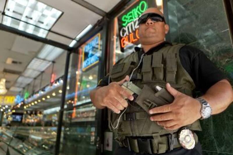 ADVANCE FOR TUESDAY SEPT. 6 - In this photo taken Thursday, Aug. 25, 2011, private security guard Gus Rodriguez stands outside "El Palacio de Oro" jewelry store in downtown Los Angeles. It’s just one aspect of the gold fever now sweeping the country’s criminal world. Law enforcement officials across the nation and beyond say they are seeing an uptick in robberies that correlates with gold’s record-high prices. (AP Photo/Damian Dovarganes)