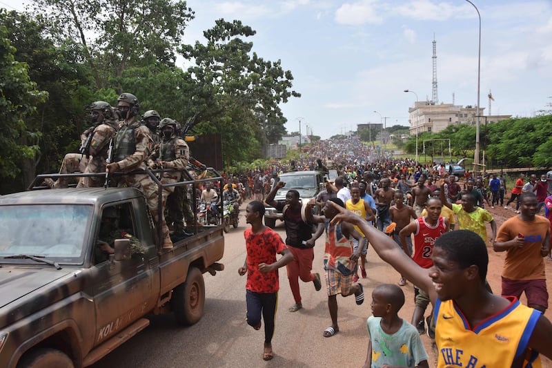 People celebrate in the streets with members of Guinea's armed forces.  AFP