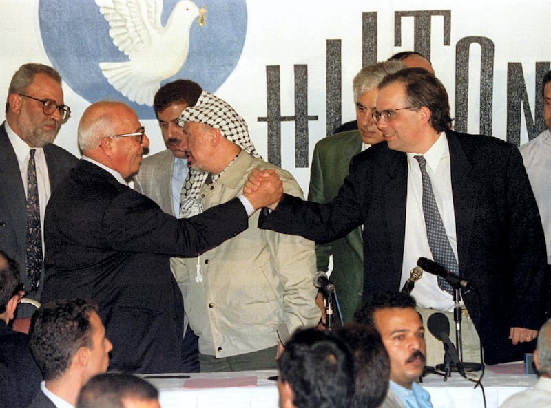 Palestinian and Israeli top negotiators Abu Ala [L] and Uri Savir [R] shake hands after signing the second phase of the Oslo peace accords September 24. PLO chairman Yasser Arafat is in the middle speaking to team member Sait Barecat, (L), after eight days of talks. The Oslo peace accords second phase will give the Palestinian self-rule of the West Bank