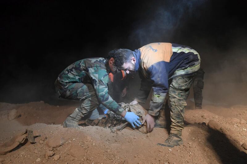 In this photo released early Saturday, Dec. 30, 2017 by the Syrian official news agency SANA, Syrian security forces members remove human remains at the site were discovered two mass graves believed to contain the bodies of civilians and troops killed by the Islamic State militants, in the village of Wawi near the northern city of Raqqa, Syria. Syrian government news agency SANA said two mass graves were discovered in the northern province of Raqqa where the Islamic State group held sway for more than three years. The agency quoted a local official as saying that work is ongoing to remove more bodies adding they are trying to identify the dead in order to hand their remains to their families. (SANA via AP)
