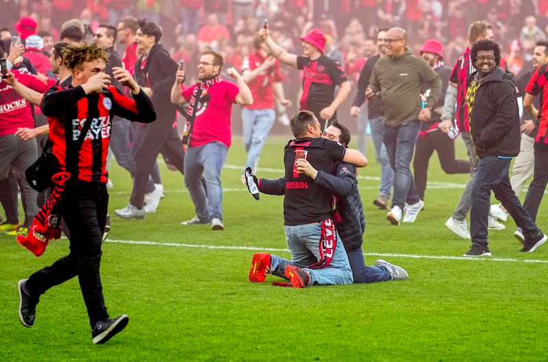 Leverkusen fans celebrate on the pitch. AP