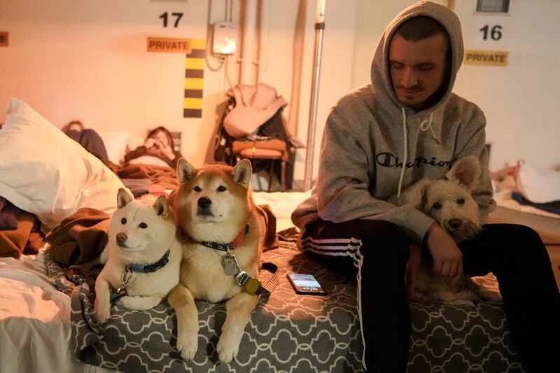 A man sits next to his dogs in an underground car park turned into a bomb shelter during an air raid alert in Kiev. AP