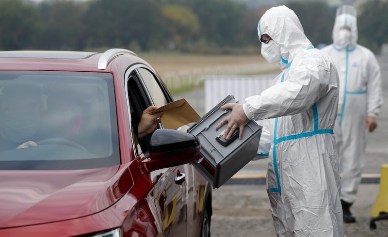 An election committee member holds a ballot box for a man to vote in regional and senate elections at a drive-in polling station in Prague, Czech Republic. AP Photo