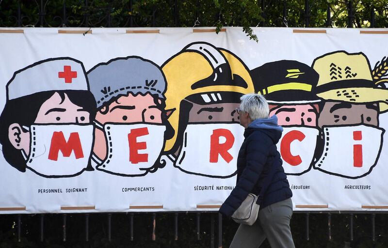 A person walks past a poster thanking the healthcare personnel, shopkeepers, the French national security, the post office staff members and farmers, in Paris.   AFP