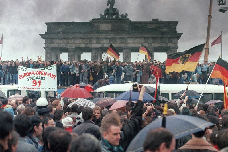 People from East Germany and West Germany gather for the opening of the Brandenburg Gate in Berlin on December 22, 1989. On November 09, Gunter Schabowski, the East Berlin Communist party boss, declared that starting from midnight, East Germans would be free to leave the country, without permission, at any point along the border, including the crossing-points through the Wall in Berlin. The Berlin concrete wall was built by the East German government in August 1961 to seal off East Berlin from the part of the city occupied by the three main Western powers to prevent mass illegal immigration to the West. According to the "August 13 Association" which specialises in the history of the Berlin Wall, at least 938 people - 255 in Berlin alone - died, shot by East German border guards, attempting to flee to West Berlin or West Germany. (Photo by PATRICK HERTZOG / AFP)