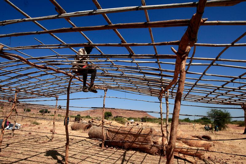 An Ethiopian refugee sets up a tent in a camp in the town of Gedaref, Sudan, after being transported from the border reception centre.
