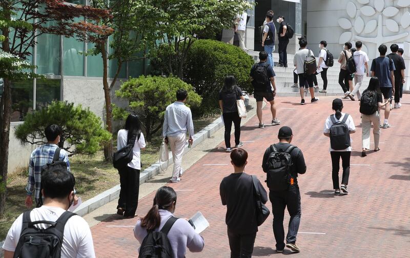 Job seekers stand in line to have their temperatures checked before a job test at a school in Seoul, South Korea.  EPA