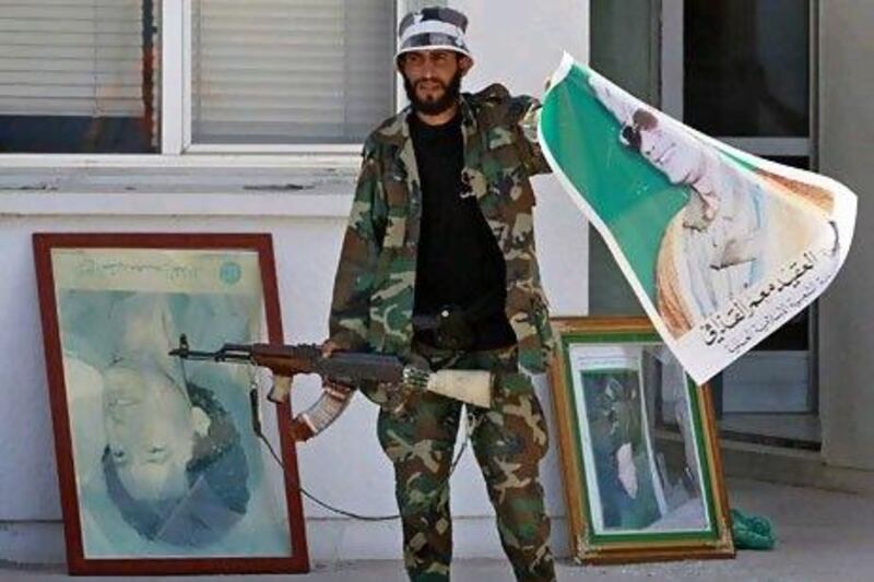 A rebel fighter holds a poster of Muammar Qaddafi in the Zawiyah oil refinery. Reuters