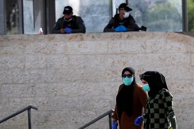 Palestinian women wearing a protective mask pass Israel policemen. EPA