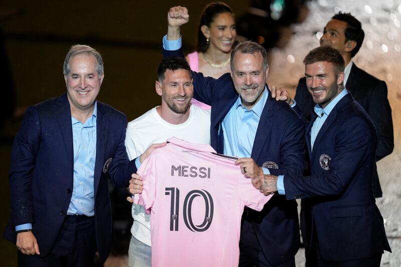 Lionel Messi holds his new Inter Miami team jersey as he poses with team co-owners Jorge Mas, left, Jose Mas and David Beckham. AP