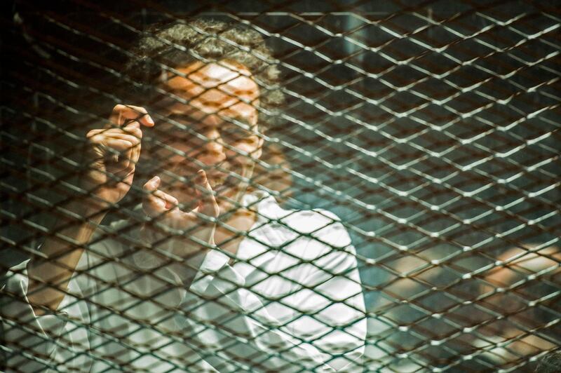 Egyptian photojournalist Mahmoud Abu Zeid, widely known as Shawkan, mimes a photographer inside a soundproof glass dock during his trial in the capital Cairo. AFP
