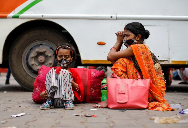 A migrant worker's family sits next to a bus at a bus station, as they wait to return to their village, after Delhi government ordered a six-day lockdown to limit the spread of the coronavirus disease, in Ghaziabad on the outskirts of New Delhi, India. Reuters