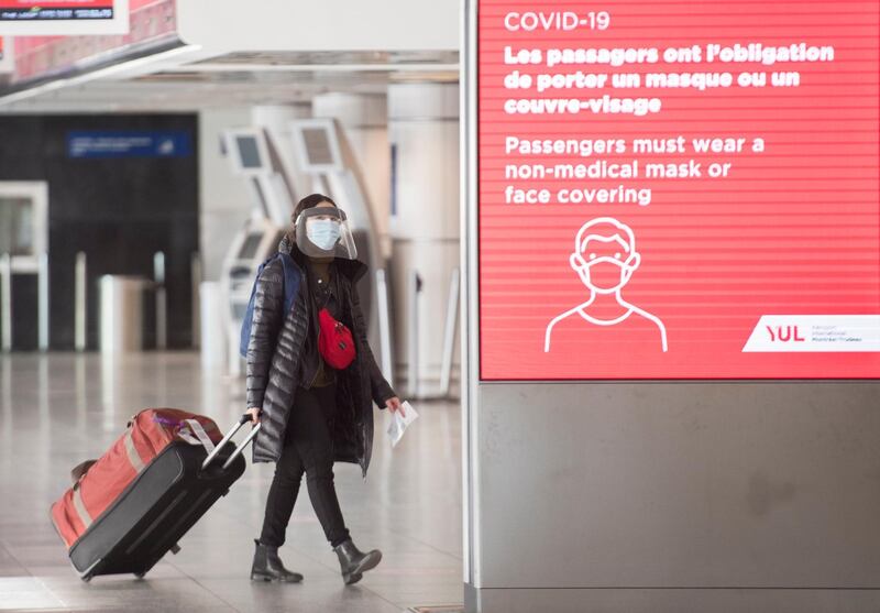 A woman wears a face mask as she walks through Montrealâ€“Trudeau International Airport in Montreal, Saturday, Dec. 19, 2020, as the COVID-19 pandemic continues in Canada and around the world.  (Graham Hughes/The Canadian Press via AP)