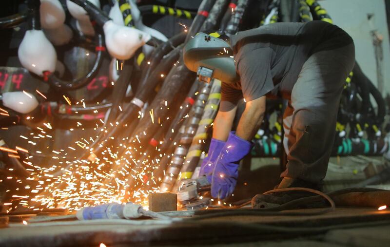 A labourer uses a metal cutting machine. EPA