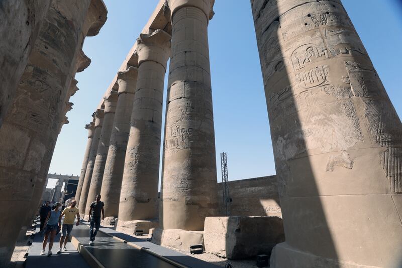 People walk among the avenue of columns.