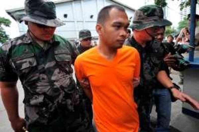 Mujibar Alih Amon (C), from the Al-Qaeda-linked Abu Sayyaf group is escorted by policemen to the custodial center inside the national police headquarters in Manila on February 25, 2010. One of the Philippines' most wanted terrorists from the Al Qaeda-linked Abu Sayyaf group has been arrested, the national police said. The man was described a "most wanted active Abu Sayyaf member", the national police said in a brief statement, without giving further details.  AFP PHOTO/TED ALJIBE *** Local Caption ***  948998-01-08.jpg