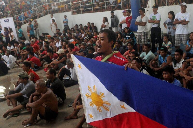 A man with a Filipino flag watches the match at the Tacloban Convention Center. Tacloban was among the hardest hit cities by Typhoon Haiyan in the Philippines. Noel Celis / AFP