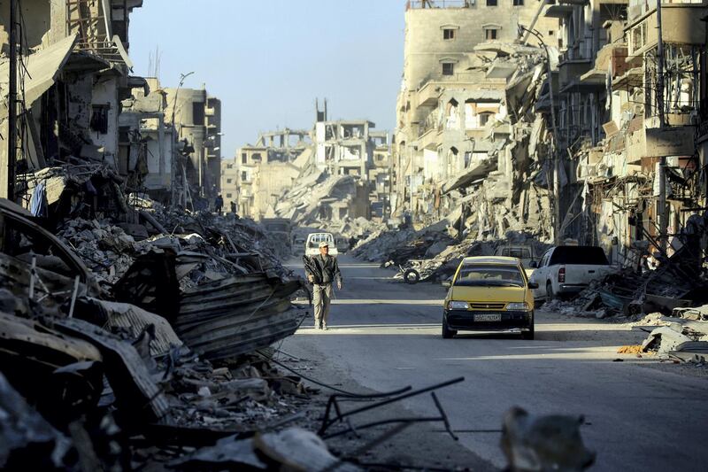 A man walks through a street in Syria's devastated city of Raqa on January 9, 2018. / AFP PHOTO / DELIL SOULEIMAN