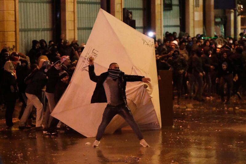 An anti-government protester prepares to throw stones at the riot police during a protest against the new government, near the parliament square, in Beirut. AP Photo